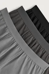 Pack de tres calzoncillos tipo bóxer de algodón elástico, con cintura elástica y costuras reforzadas. Incluye tonos negro, gris oscuro y gris claro.