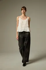 Musculosa negra de breteles finos, confeccionada en algodón con diseño plisado y detalles de encaje. Presenta un corte holgado con volados en el ruedo y escote profundo.