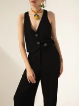 Pantalón negro de crepe con cintura cruzada, broche con brillo glitter, tiro alto, pinzado y pata ancha.