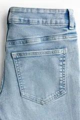 Jean de denim celeste claro con efecto desteñido, tiro bajo, corte ajustado en la parte superior y piernas acampanadas.