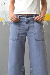 Pantalón de jean color crudo, de corte palazzo con aberturas en el ruedo y bolsillos laterales.