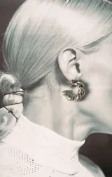 Aro tipo argolla de metal plateado con diseño trenzado.