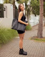 Bolso tipo tote de cuero negro, hecho a mano, con detalle de costura decorativa en el borde superior y asas largas para llevar al hombro.