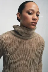 Jersey de punto calado color beige, con cuello alto vuelto y manga larga, confeccionado en lino.