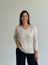 Sweater de punto fino en color beige, con escote en V y mangas largas con puños ajustados.