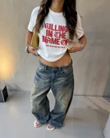 Remera blanca de manga corta, con cuello redondo y diseño estampado en el centro con la frase "Killing in the name of" en color rojo.