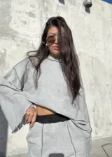 Buzo oversize de color gris, con diseño de costuras expuestas en contraste y terminaciones desflecadas en mangas y ruedo.