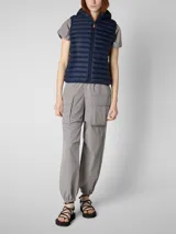 Chaleco acolchado ligero color azul marino con capucha, cierre frontal naranja y bolsillos laterales. Confeccionado con relleno sintético Plumtech.