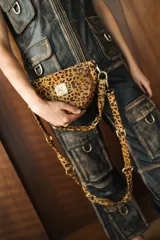 Bandolera con silueta de media luna y diseño estructurado. Confeccionada en cuero con estampado animal print, cuenta con cierre superior, herrajes metálicos dorados y correa regulable para usar al hombro o cruzada.