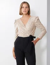 Enterito combinado de fiesta marca Julia Jordan. El torso es de lentejuelas color beige con escote en V cruzado y mangas largas abullonadas. La cintura es elastizada con lazo de ajuste y el pantalón es negro con bolsillos verticales. La espalda tiene cierre invisible y el torso está forrado.