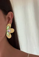 Aros dorados con forma de flor, con cristales facetados de vidrio verdes y tornasol en el centro.