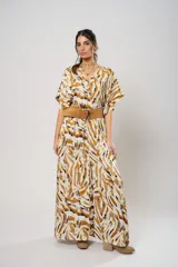 Vestido largo con estampado animal print en tonos camel, blanco y negro. Tiene escote en V, mangas cortas tipo murciélago y tajo frontal. Incluye cinturón ancho de cuero color camel.