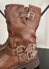 Bota tipo biker de caña media en cuero vegano color marrón, con suela track y múltiples correas con hebillas metálicas plateadas en el tobillo y la parte superior de la caña.