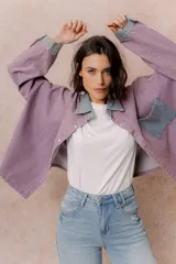 Camisa lila de calce relajado y manga larga, con cuello clásico, puños y bolsillo delantero en denim contrastante. Cierre frontal con broches metálicos.