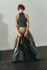 Top de punto jaspeado en color gris oscuro, con cuello alto y diseño halter sin mangas. Confeccionado con una mezcla que incluye lana, presenta terminaciones acanaladas en el cuello y el ruedo.