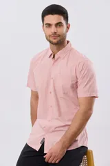 Camisa lisa de algodón azul marino, de manga corta, con cuello camisero, cierre frontal de botones y un bolsillo aplicado en el pecho.