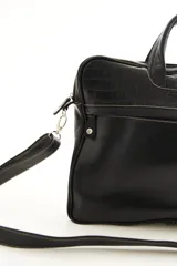 Portafolio de cuero vacuno marrón, con doble asa superior, correa ajustable desmontable y bolsillo frontal con cierre. Presenta detalles de textura símil reptil en la parte superior.
