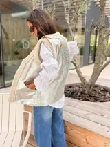 Chaleco reversible de corte recto, con un lado en acabado metalizado plateado y el otro en textura de corderito sintético color crema. Presenta bolsillos laterales y diseño sin mangas.