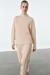 Falda midi de punto color rosado con efecto arrugado, cintura elástica y detalle de volados en la parte superior.