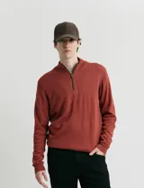 Sweater de punto color verde oliva, con cuello alto y medio cierre frontal. Presenta coderas en símil nappa y puños acanalados.