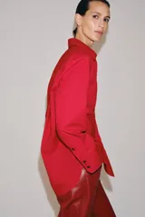 Camisa oversize verde de popelina de algodón, con cuello solapa, manga larga y cierre frontal con botones ocultos bajo solapa.