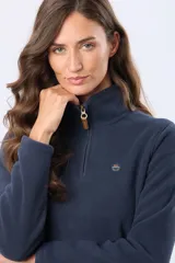 Buzo de polar color crema con cuello alto y cierre frontal parcial. Presenta detalles en cuero en el tirador del cierre y un pequeño bordado en el pecho y en la manga.