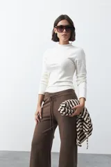 Pantalón de punto de corte relajado, con pierna recta y caída fluida. Presenta cintura elástica con cordón de ajuste y diseño liso en color marrón.