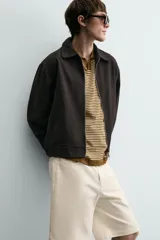 Bermuda de algodón color beige claro, de corte relajado y largo hasta la rodilla. Presenta cierre frontal con cremallera y botón, bolsillos delanteros y bolsillo cerillero, además de bolsillos traseros de plastrón.