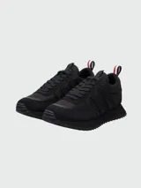 Zapatillas Moncler modelo Pacey de color negro, con diseño de caña baja y suela dentada. Presentan detalles en gamuza y nylon, y una presilla trasera con los colores tricolores de la marca.
