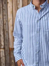 Camisa de manga larga a rayas verticales azules y blancas, con cuello abotonado, bolsillo en el pecho y corte regular.