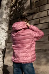 Campera puffer ultraliviana color beige, con diseño acolchado horizontal, capucha incorporada, cierre frontal y bolsillos laterales.
