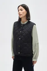 Chaleco acolchado de color negro con diseño de rombos, cierre frontal con botones metálicos a presión y dos bolsillos delanteros aplicados.