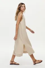 Vestido midi color crudo de corte relajado, con caída fluida, sin mangas y escote en V.