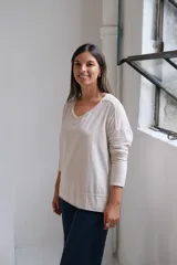 Remera de algodón color beige, con cuello en V, mangas largas con costuras caídas y ruedo con detalle de costura horizontal.