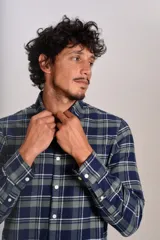 Camisa de manga larga confeccionada en tejido de franela con estampado de cuadros en tonos azul marino y verde. Presenta cuello abotonado, cierre frontal con botones y un bolsillo en el pecho con el logo bordado de la marca.