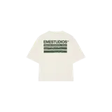 Remera oversize color arena con estampado gráfico verde en la espalda con el texto 'EMESTUDIOS' y elementos de diseño lineal.