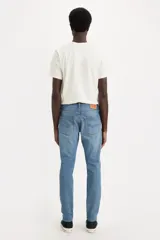 Jean de corte slim taper en color azul medio, de tiro medio con diseño de cinco bolsillos y efecto ligeramente deslavado.