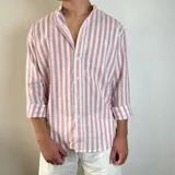 Camisa de manga larga con cuello mao, confeccionada en tejido de lino con estampado de rayas verticales en tonos amarillo y blanco. Presenta cierre frontal con botones y un pequeño bordado en el pecho.