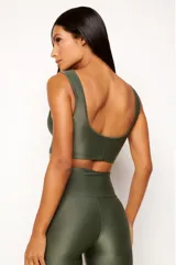 Top deportivo color terracota, de corte crop y manga sisa, con cuello redondo y espalda escotada. Presenta textura acanalada y acabado brillante.