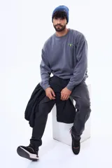 Buzo de felpa gris con cuello redondo y corte oversize. Presenta una estampa gráfica en la espalda que ilustra un vaso con una rodaja de lima y texto en colores verde y blanco.