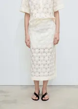 Falda midi de corte recto con diseño calado y flores en relieve. Presenta tiro medio, abertura lateral en el bajo y cierre de cremallera lateral. Incluye forro interior.