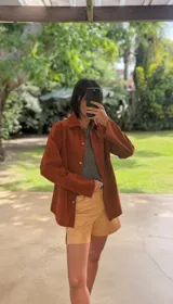 Camisa de cuero color marrón óxido, con cuello clásico, cierre frontal con botones a tono y mangas largas.