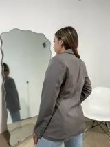 Blazer sastrero de corte clásico en color gris, con solapas de muesca, cierre frontal de un botón y bolsillos laterales con solapa.