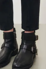 Jean de corte mom en color negro, con diseño de tiro alto, cinco bolsillos y detalle de rotura en la rodilla izquierda.