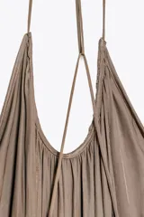 Vestido largo satinado color marrón topo, de escote redondo y tirantes finos cruzados en la espalda. Bajo asimétrico redondeado. Zara Woman Collection.