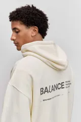 Buzo con capucha de corte holgado, color crema, con bolsillo frontal tipo canguro y pequeña estampa tipográfica en el pecho.