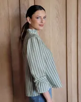 Blusa de algodón color azul, de corte suelto, con mangas largas abullonadas y cuello con volados y escote en V.