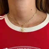 Collar dorado con cadena de eslabones rectangulares y dije de estrella de ocho puntas con un cristal en el centro.