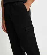 Pantalón cargo de hombre color negro, confeccionado en sarga de algodón, con cintura elástica, bolsillos laterales tipo cargo y bolsillos traseros.