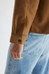 Sobrecamisa de H&M en tejido de efecto gamuza color marrón, con cuello inglés, cierre frontal de botones, un bolsillo en el pecho y mangas largas con puños abotonados.